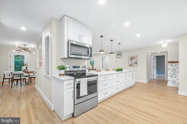 a large kitchen with stainless steel appliances kitchen island granite countertop a stove a sink a refrigerator a dining table and chairs with wooden floor
