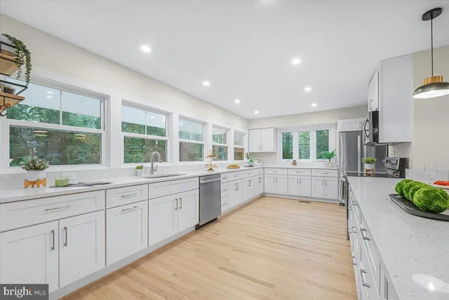 a large white kitchen with lots of counter space windows and a sink