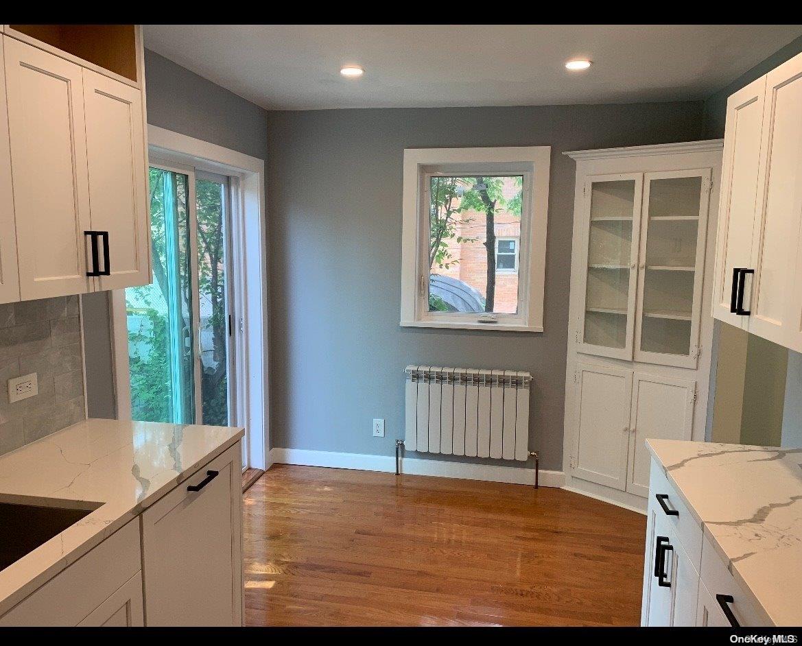 76-22 57th Road Queens, NY 11379 - Photo 5 of 9 a view of an empty room with a window and wooden floor