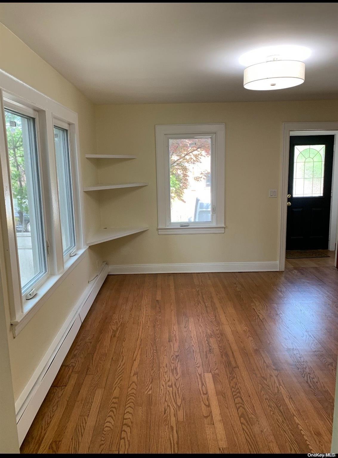 76-22 57th Road Queens, NY 11379 - Photo 6 of 9 wooden floor in an empty room with a window