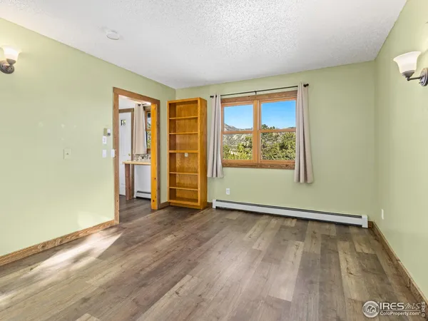 a view of an empty room with wooden floor and closet