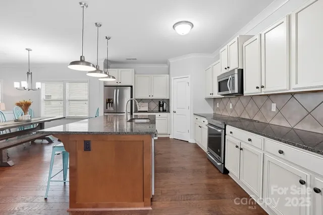 a kitchen with stainless steel appliances granite countertop a sink a stove and a wooden floors
