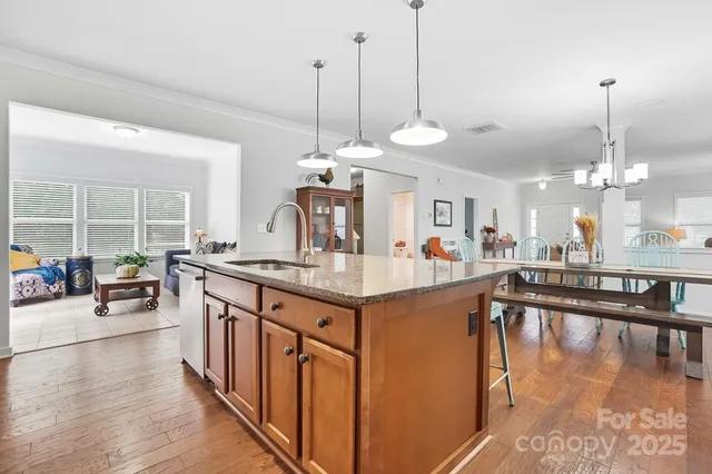 a kitchen with kitchen island granite countertop a sink a counter top space and living room view