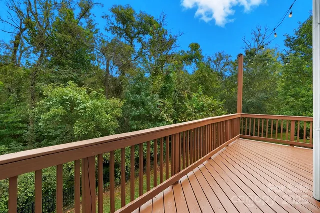a balcony with wooden floor and trees in the back