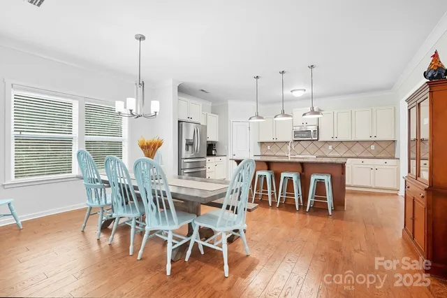 a view of a dining room and livingroom with furniture wooden floor a chandelier