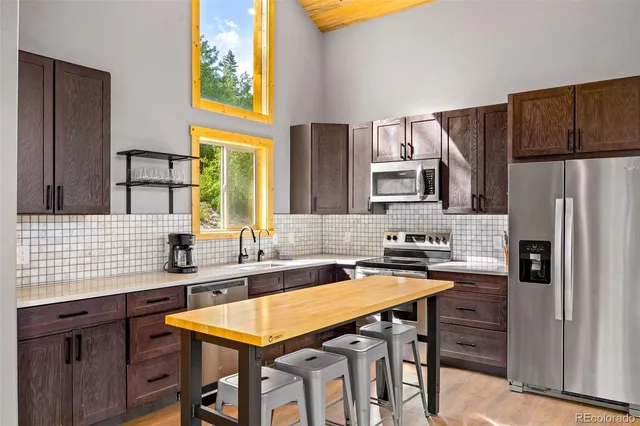 a kitchen with stainless steel appliances granite countertop a sink a stove a refrigerator and cabinets