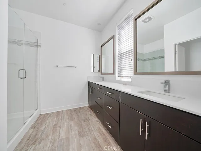 a spacious bathroom with a double vanity sink a mirror and a shower