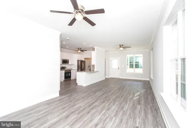 a view of an empty room with a window and wooden floor