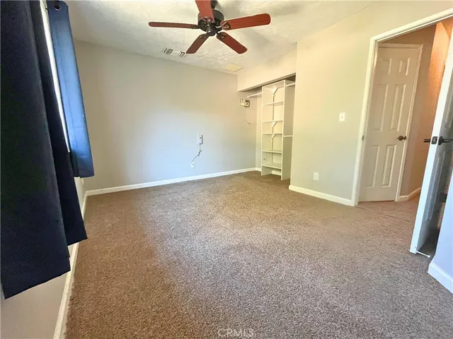 an empty room with closet and a ceiling fan