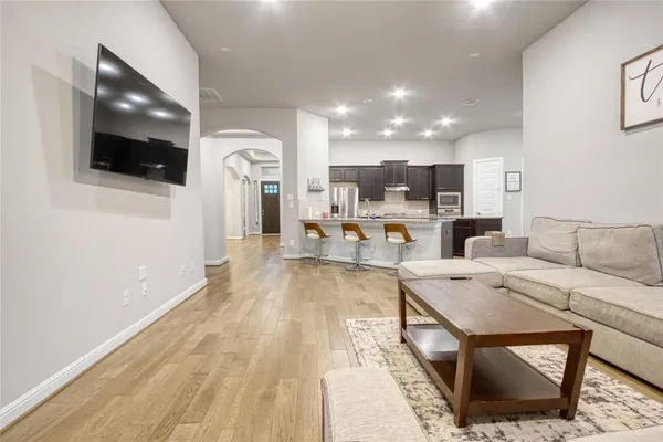 a living room with stainless steel appliances furniture a rug and a view kitchen