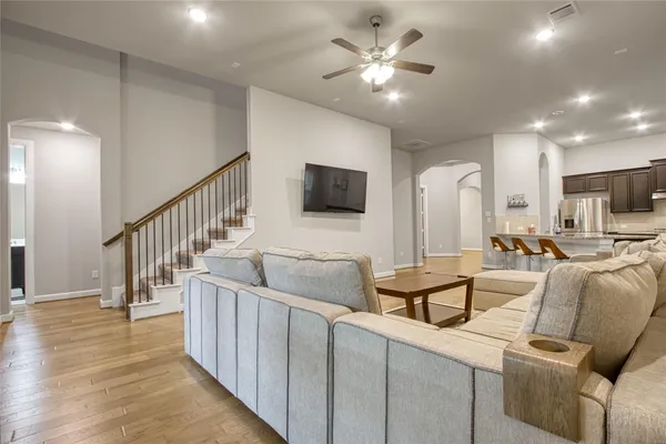 a living room with couches and a flat screen tv with kitchen view