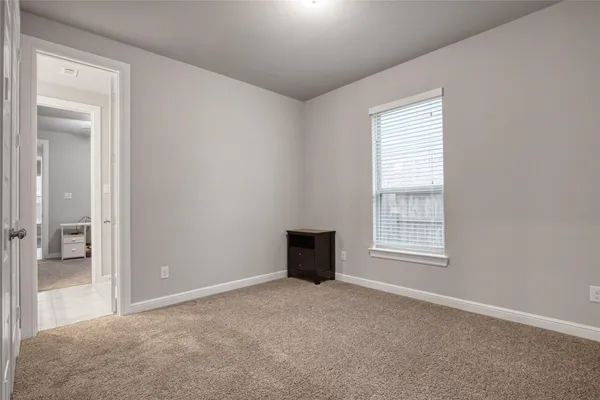an empty room with chandelier fan and windows