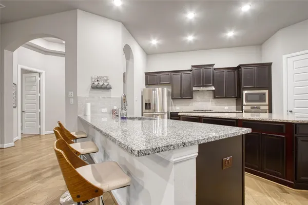 a kitchen with stainless steel appliances granite countertop a sink refrigerator and cabinets