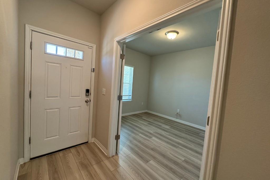 12604 Dairywork Road Buda, TX 78610 - Photo 2 of 20 Step into a luminous entryway, featuring sleek hardwood flooring leading to an adjacent, adaptable space.