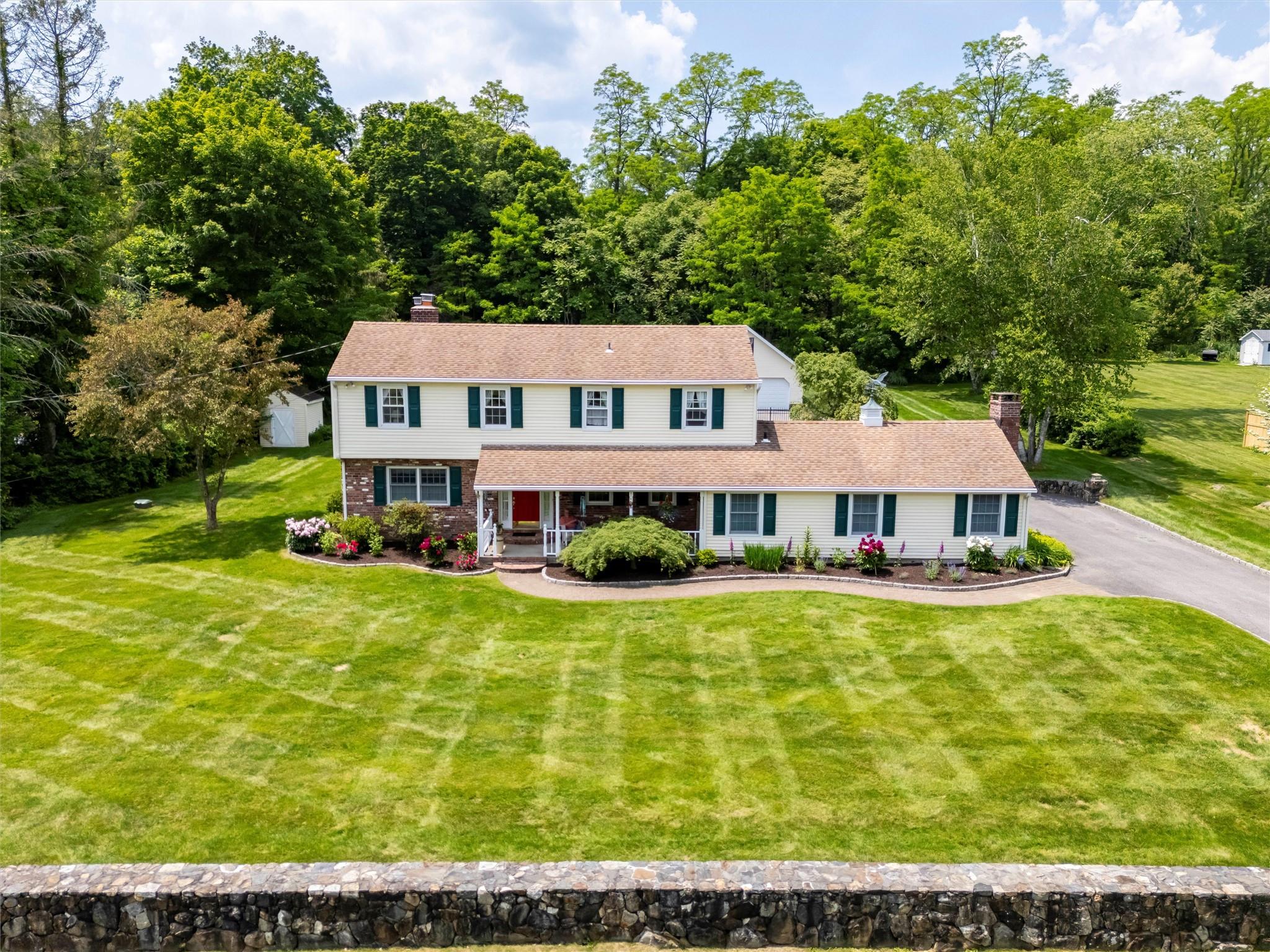 View of front facade with a chimney, covered porch, a front lawn, and brick siding