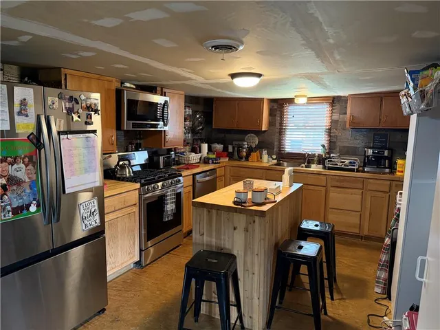 a kitchen with stainless steel appliances granite countertop a sink a stove a refrigerator cabinets and a dining table