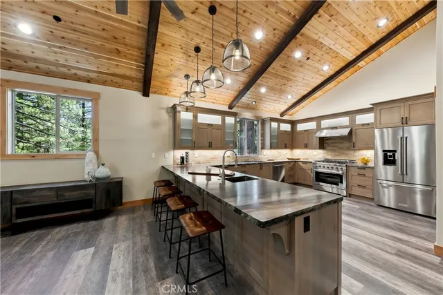 a kitchen with stainless steel appliances granite countertop a sink a stove and a wooden floors