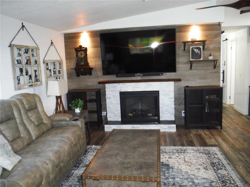168 Pinewood Terrace, Unit 104 Safety Harbor, FL 34695 - Photo 14 of 55 a living room with furniture a flat screen tv and a fireplace