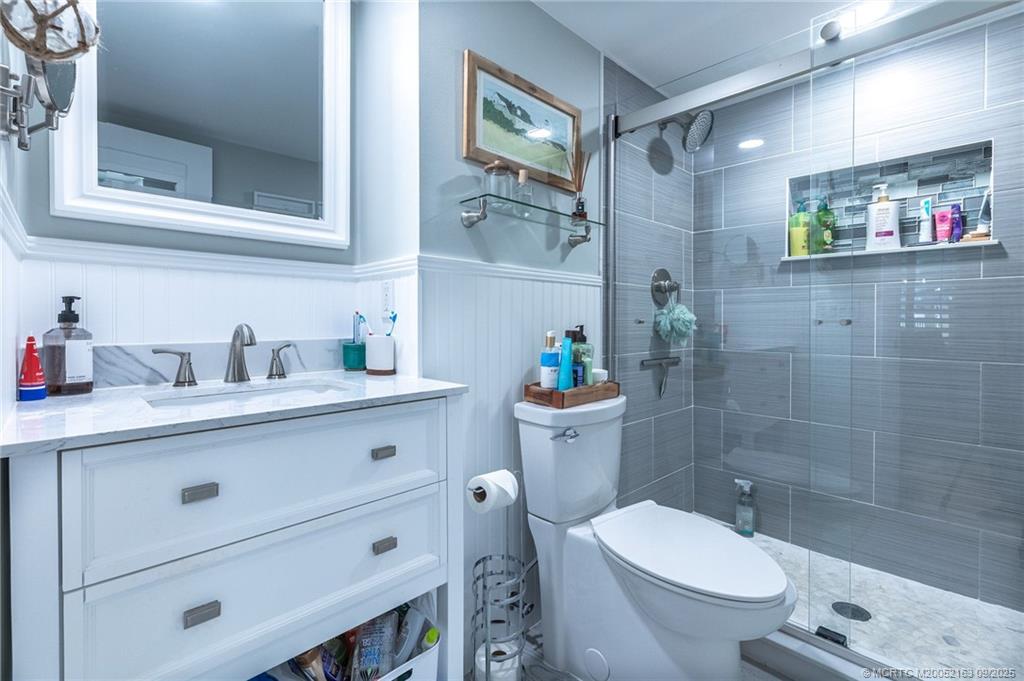 245 Northeast MacArthur Boulevard, Unit 18 Stuart, FL 34996 - Photo 12 of 15 a bathroom with a granite countertop toilet sink and mirror