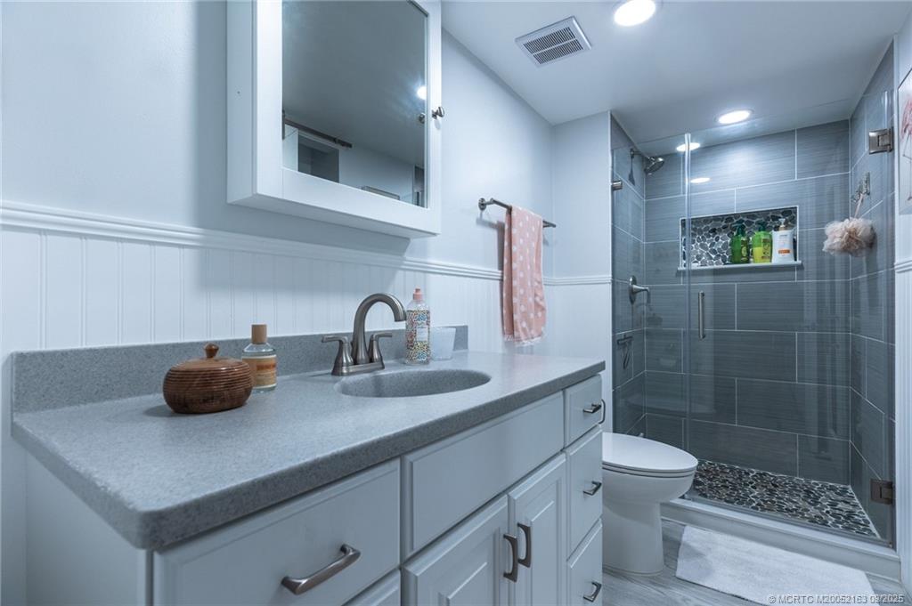 245 Northeast MacArthur Boulevard, Unit 18 Stuart, FL 34996 - Photo 3 of 15 a bathroom with a sink a toilet and shower