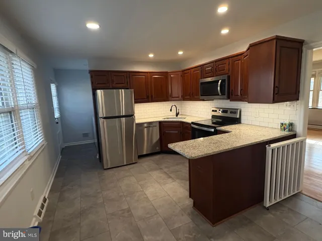a kitchen with stainless steel appliances granite countertop a refrigerator a stove a sink and a microwave