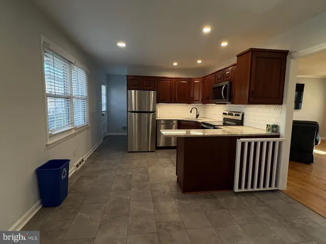 a kitchen with kitchen island granite countertop a refrigerator and a stove top oven