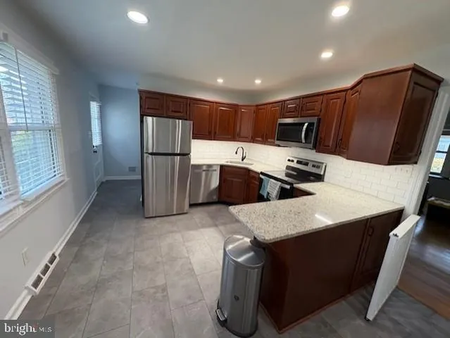 a kitchen with stainless steel appliances kitchen island sink refrigerator and microwave