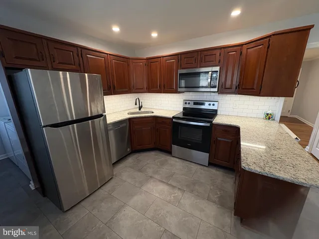 a kitchen with stainless steel appliances granite countertop a refrigerator stove a sink and a microwave