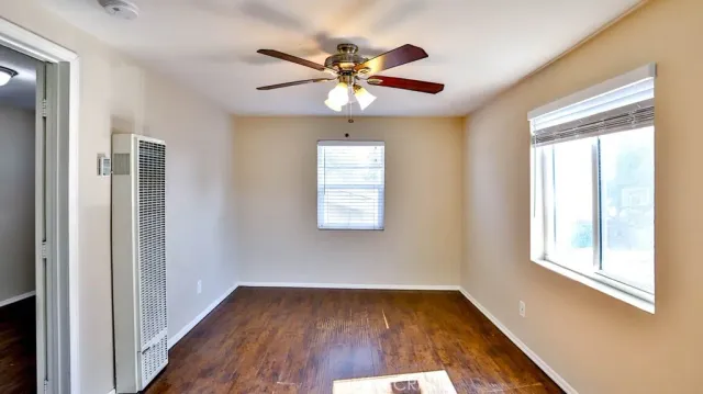 a view of empty room with wooden floor and fan