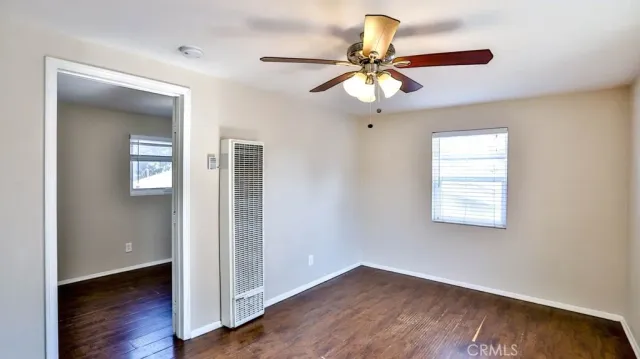 an empty room with wooden floor fan and windows