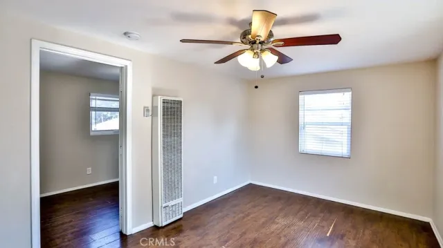 an empty room with wooden floor fan and windows