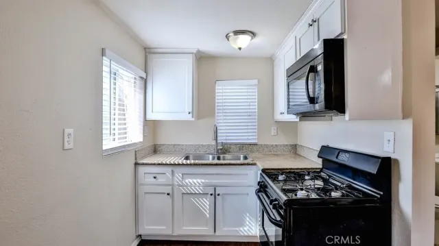a kitchen with granite countertop a stove a sink and a microwave