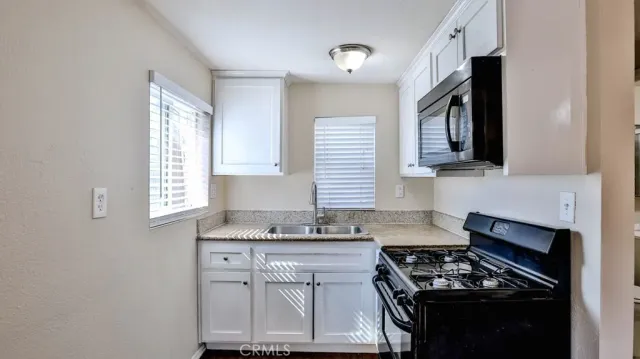 a kitchen with granite countertop a stove a sink and a microwave