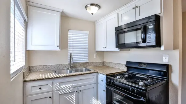 a kitchen with stainless steel appliances granite countertop a stove a sink and a microwave
