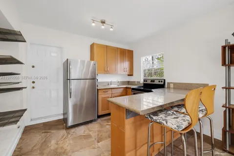 a kitchen with granite countertop a refrigerator a stove a sink a dining table and chairs