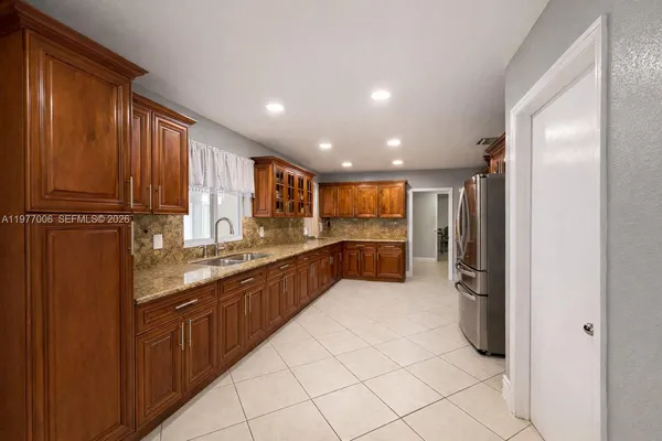 a large kitchen with stainless steel appliances granite countertop a refrigerator and a sink