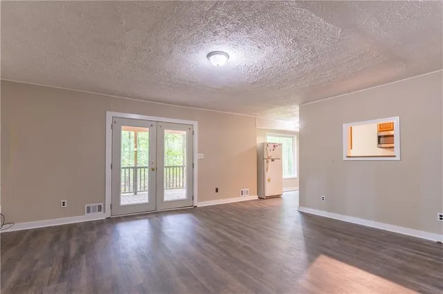 a view of an empty room with wooden floor and window