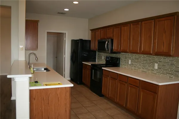 a kitchen with kitchen island a sink refrigerator and microwave