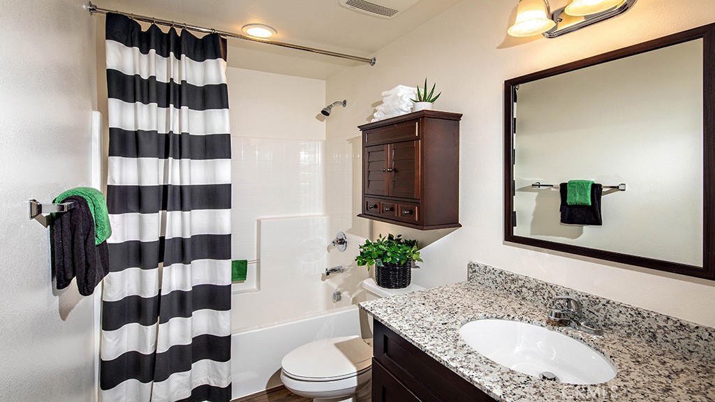 14068 Hera Place Beaumont, CA 92223 - Photo 6 of 14 a bathroom with a granite countertop sink a toilet a shower and a mirror