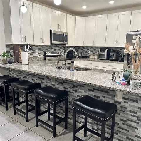 a kitchen with stainless steel appliances granite countertop a stove a sink a microwave and white cabinets
