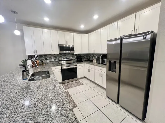 a kitchen with stainless steel appliances granite countertop a stove a sink a refrigerator and cabinets