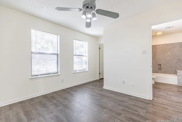 a view of an empty room with a window and wooden floor