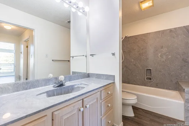 a bathroom with a granite countertop sink toilet and shower