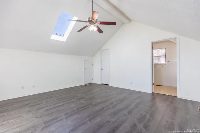 an empty room with wooden floor fan and windows