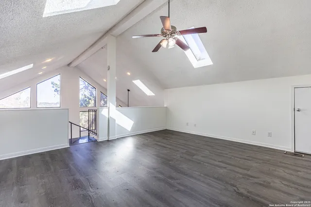 an empty room with wooden floor ceiling fan and windows