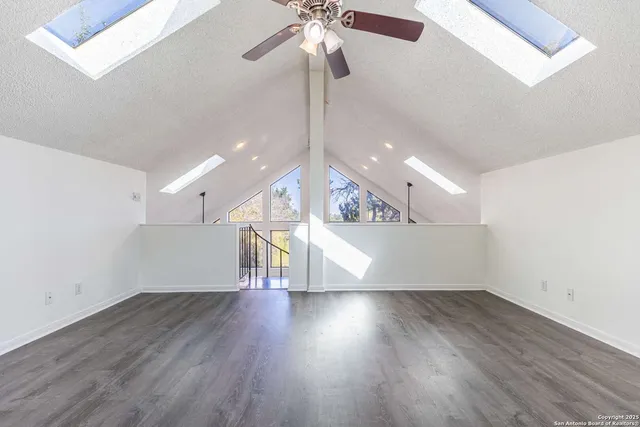 a view of an empty room with wooden floor and a ceiling fan
