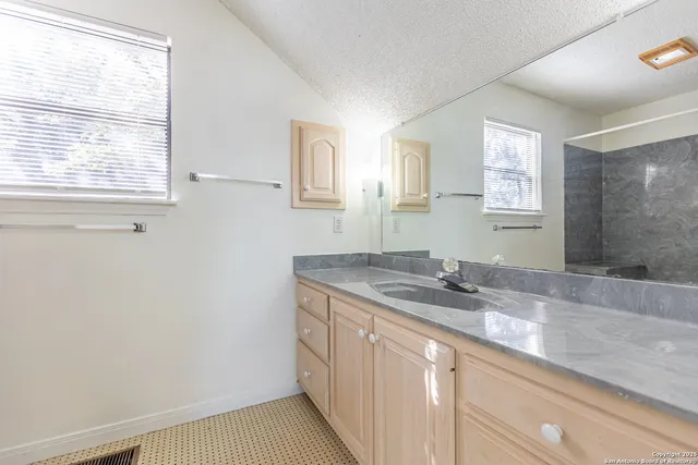 a bathroom with a granite countertop sink a mirror and a window