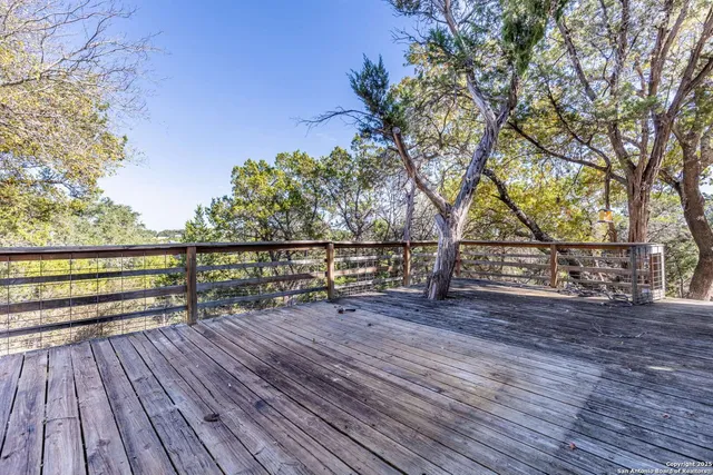 a view of deck with wooden floor and fence with a large tree