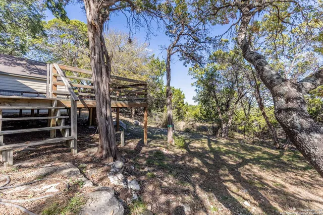 a backyard of a house with table and chairs under an umbrella