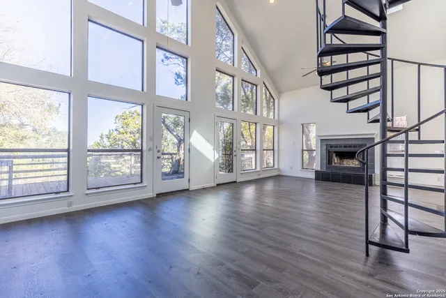 an empty room with wooden floor fireplace and windows
